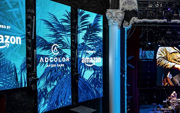 ADCOLOR After Dark LED panels beside a venue column, carrying the palm artwork and the sponsor lockup.