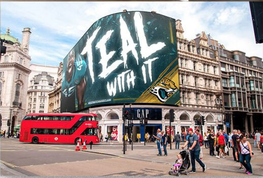 A Teal With It digital billboard on a city high street.