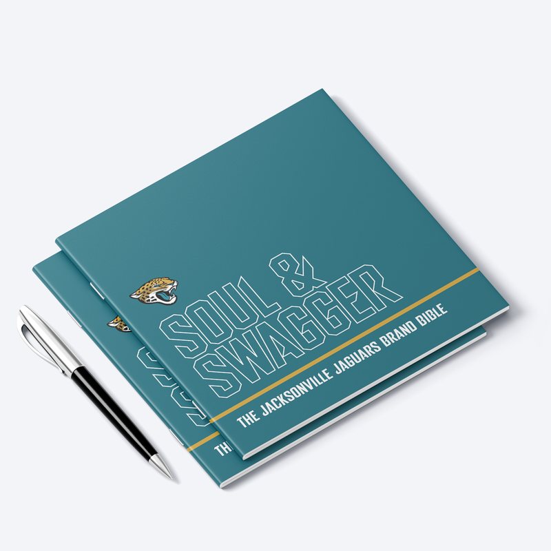 The Soul and Swagger brand book closed on a desk, the title set in teal and white with the jaguar head above it.
