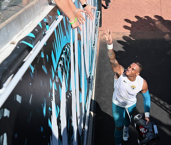 A player reaching up to high-five fans leaning over the rail on his way in from the field.