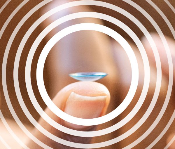 A contact lens balanced on a fingertip, framed by the campaign's concentric ring treatment.