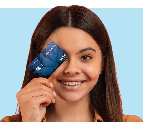 A member holding a Northwest Federal Visa card up to her eye.